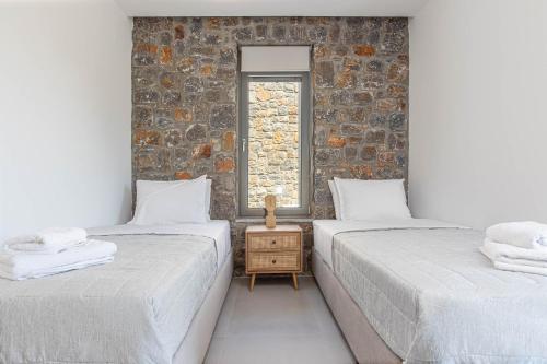 two beds in a room with a brick wall at Apoikia Villas Pefkochori in Pefkohori