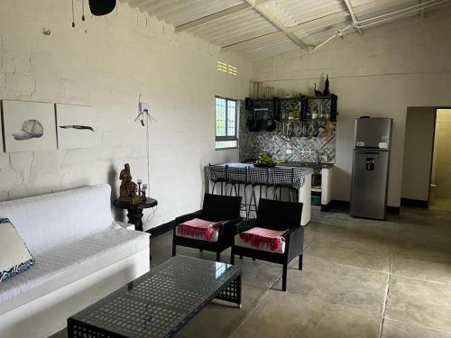 a living room with a couch and chairs and a refrigerator at Hermosa cabaña amoblada en Pueblo Bello, Sierra Nevada in Pueblo Bello