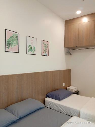 two beds in a room with three pictures on the wall at Austin @ Novo 8 in Malacca