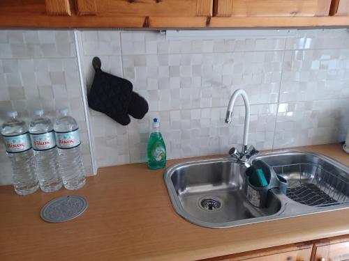 a kitchen counter with a sink and bottles of water at Frygano Apartments 1 in Oítilon