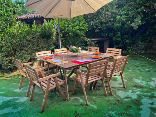 a wooden table with chairs and an umbrella at Casa rural Paraje de Yuste in Cuacos de Yuste