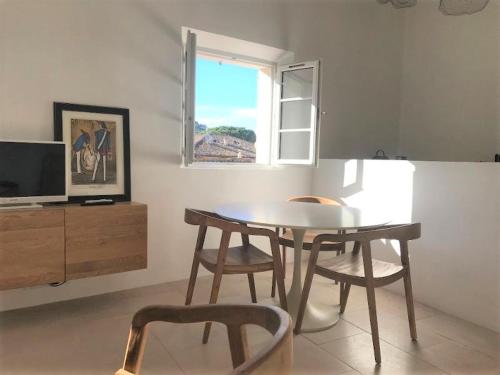 a dining room with a table and chairs and a window at VILLAGE - DUPLEX lumineux avec vue magnifique sur les toits in Saint-Tropez