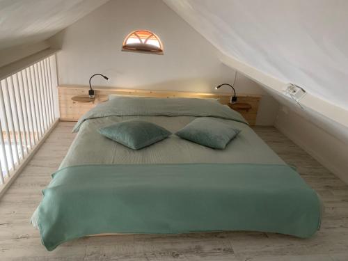 a bedroom with a large green bed with two pillows at B&B Achterom in Thorn