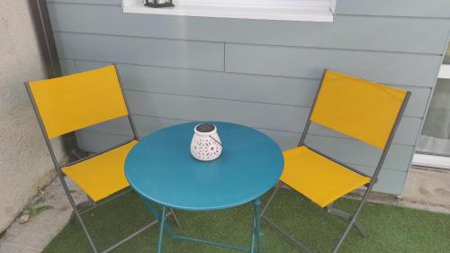 a blue table with three chairs and a vase on it at La Casita: Studio cosy indépendant de 25 m² in Les Sables-dʼOlonne