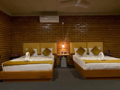 Zimmer mit 2 Betten und einem Tisch mit einer Lampe in der Unterkunft Elephant Arcade in Tissamaharama