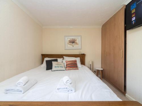 ein Schlafzimmer mit einem weißen Bett und Handtüchern darauf in der Unterkunft Pass the Keys Spacious Cosy Home Close To London Abbey Wood in London