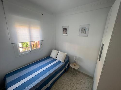 una piccola camera con letto blu e finestra di Casa Luz y Azahar a San Juan del Puerto