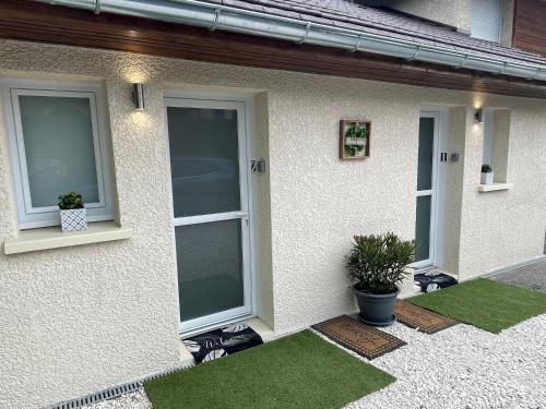 une maison blanche avec deux fenêtres et de l'herbe verte dans l'établissement JARDIN PRIVÉ 2, à La Ravoire
