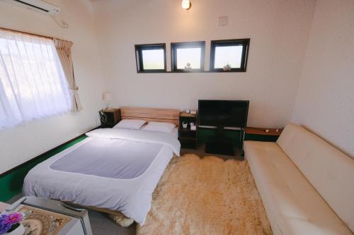 two beds in a room with a couch and a tv at セーナーニカントリーイン in Sammu