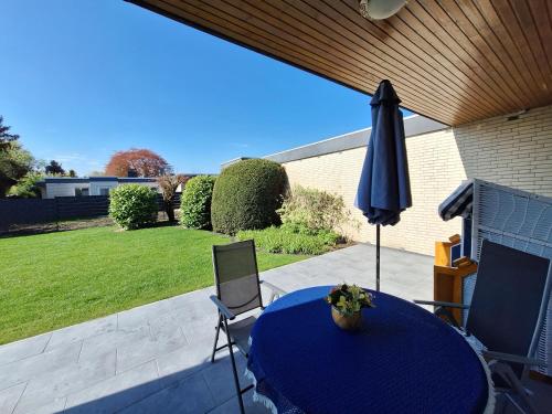un patio con una mesa azul y una sombrilla en Ferienhaus Nordseebrise Sonnenterrasse, zentral und ruhig, en Horumersiel
