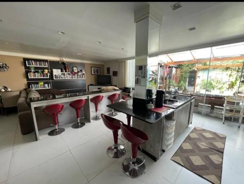a kitchen with a bar with red stools at Hostel AJBJ Turismo in Curitiba