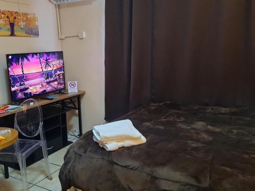 a bedroom with a bed and a desk and a television at Paradise Comfort in Koror