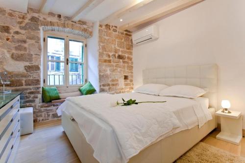 ein Schlafzimmer mit einem großen weißen Bett und einer Ziegelwand in der Unterkunft Luxury San Giovanni Apartment 2 in Split