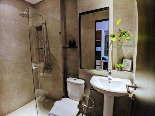 a bathroom with a toilet and a sink and a shower at The Mango Suites by Flat06 in Jakarta