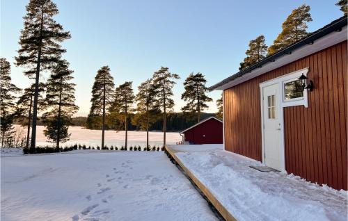 a red building with a white door in the snow at Beautiful Home In Idkerberget With 2 Bedrooms in Grangärde