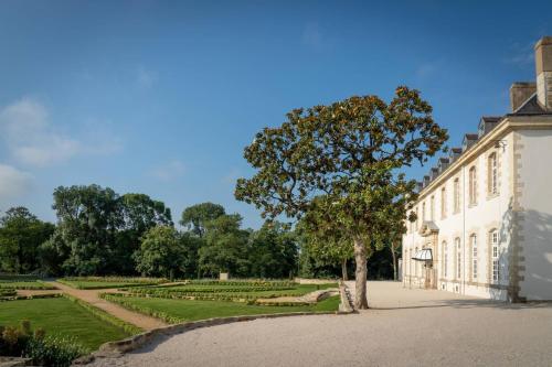 a tree in front of a building with a garden at Abbaye De Villeneuve in Les Sorinières