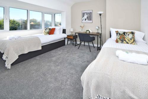 a bedroom with two beds and a desk and window at Lily House by YourStays - Cosy 3 Bedroom House in Crewe in Crewe