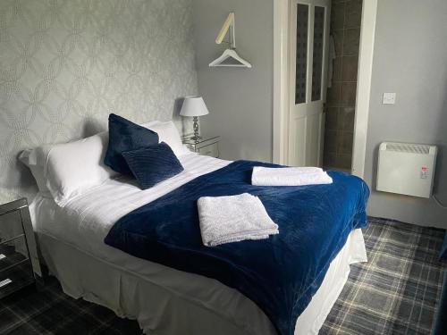 a bed with blue and white sheets and pillows at Fox House Thirdpart Farm in Beith