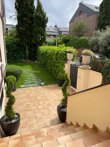 Moderna Casa de Lujo con Jardín y Barbacoa في مدريد: حديقة فيها نباتات في قدور على الفناء