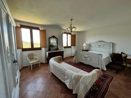 a bedroom with a bed and a chair and windows at Country house lu sambignu in San Pasquale