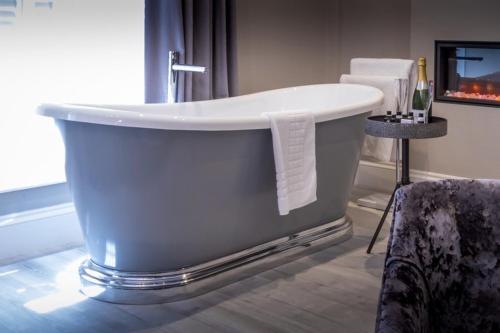 Wolfscastle Country Hotel في هافرفوردوست: حوض استحمام في غرفة الفندق مع كرسي