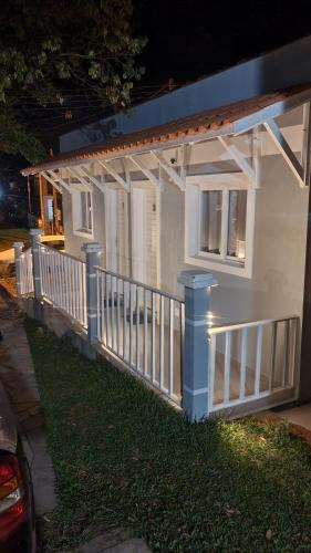uma casa com uma cerca branca e um alpendre em Hospedagem Pierina em Gramado