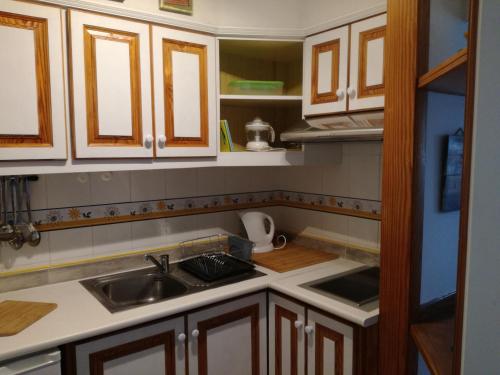 una cocina con armarios de madera y fregadero en Antomax Apartment in Costa del Silencio - WI FI, en Costa del Silencio