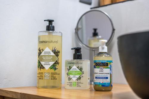 three bottles of disinfectants sitting on a wooden table at L'Odyssée provençale, un duplex de charme de 2 chambres au pied du village médiéval de Bormes-les-Mimosas, offrant des prestations haut de gamme et une superbe vue sur le Massif des Maures in Bormes-les-Mimosas