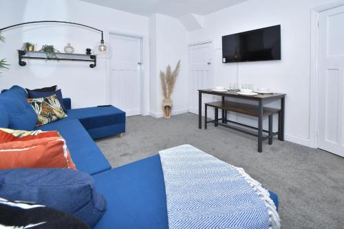 a living room with a blue couch and a table at Lily House by YourStays - Cosy 3 Bedroom House in Crewe in Crewe