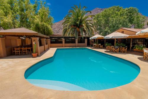 a large blue swimming pool with tables and chairs at Cabañas Refugio El Molle in El Molle