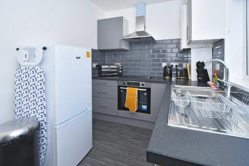 a kitchen with a white refrigerator and a sink at Lily House by YourStays - Cosy 3 Bedroom House in Crewe in Crewe
