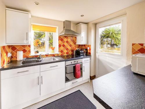 a kitchen with white cabinets and a window at Tramways in Carnbrea