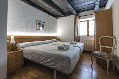 a bedroom with a bed and a chair and a window at Hostal Etxeberri in Eugi