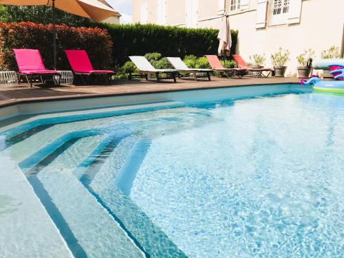 une grande piscine avec des chaises et des chaises roses dans l'établissement Domaine Pont Juillet, à Fontaines