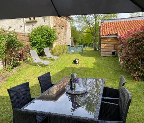 einen Tisch und Stühle in einem Hof mit einem Hund in der Unterkunft Gîte du Rossignol entre lac et forêt in Mervent