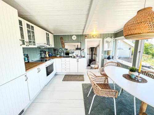 uma cozinha com armários brancos e uma mesa e cadeiras em Summer cabin by the sea Holmsbu. (40 min from Oslo) em Asker