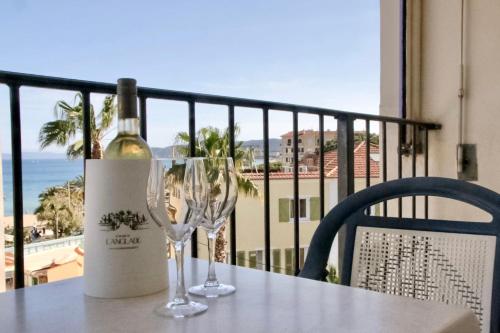 - une bouteille de vin assise sur une table avec deux verres dans l'établissement Anglade Hotel, au Lavandou