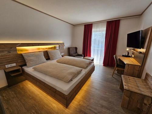 een slaapkamer met een bed, een bureau en een televisie bij Hotel-Landgasthof Ploss in Schönwald