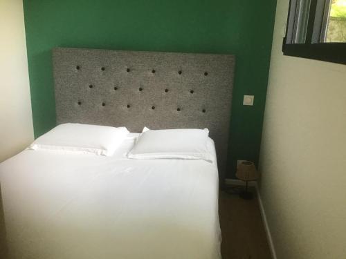 a bedroom with a white bed with a green wall at Hôtel Le Saint Martin in Sablé-sur-Sarthe