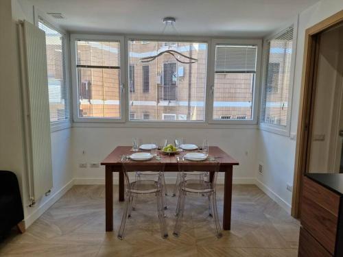 a dining room with a wooden table and some windows at Casa Camilla in Rome