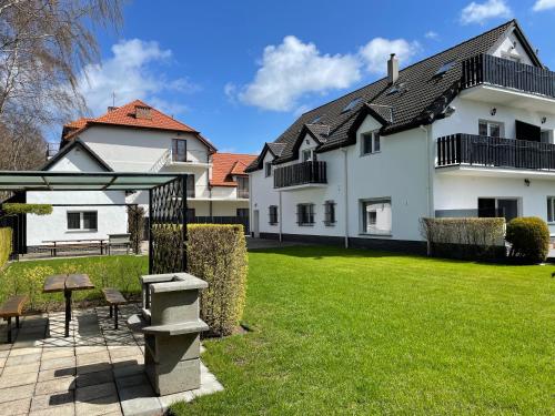 a large white house with a grass yard at Villa & Domek Maja in Sarbinowo