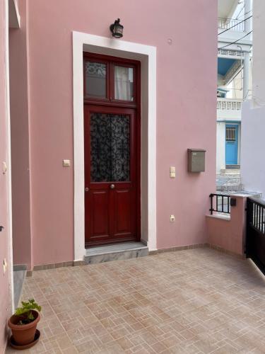 エルムポリにあるErmoupoli, Syros City Apartmentsのピンクの建物の横の赤い扉