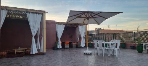 a patio with white chairs and an umbrella at Marrakech medina inn in Marrakesh