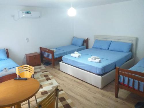 a room with two beds and a table and a table and chairs at Kulla e Vjeter (Bar Restaurant, Guesthouse, Parking and Camping) in Koman