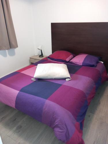 - un grand lit avec des draps et des oreillers violets et roses dans l'établissement T2 avec piscine aux portes d'Honfleur, à Honfleur