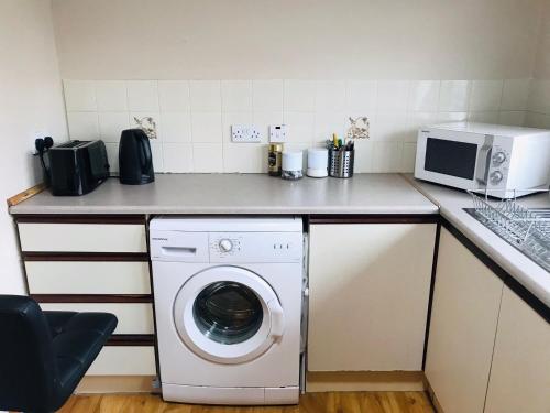 a kitchen with a washing machine and a microwave at Lovely 3 bedroom apartment in Buncrana in Buncrana
