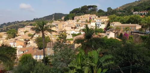 a village on the side of a hill with houses at L'Odyssée provençale, un duplex de charme de 2 chambres au pied du village médiéval de Bormes-les-Mimosas, offrant des prestations haut de gamme et une superbe vue sur le Massif des Maures in Bormes-les-Mimosas