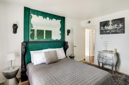 a bedroom with a bed with a green headboard at Chic Dallas Condo with Pool, Walk to Knox Street! in Dallas