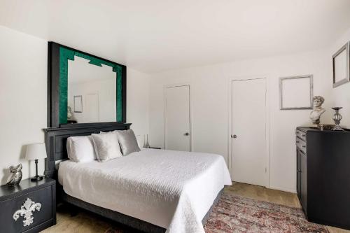 a white bedroom with a bed and a mirror at Chic Dallas Condo with Pool, Walk to Knox Street! in Dallas