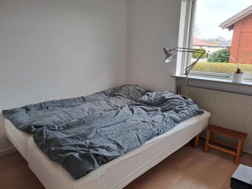 een ongemaakt bed in een kamer met een raam bij VindPust in Varde